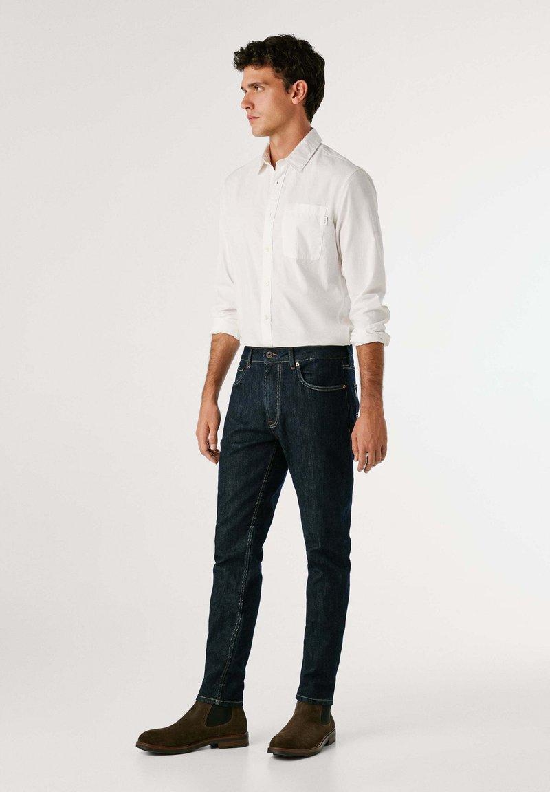 Dunkle Jeans mit Hemd und klassischen Chelsea Boots
